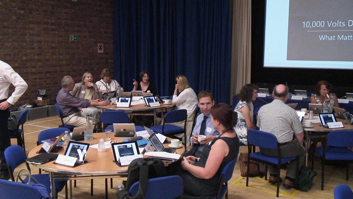 Open University participants discussing their experiences around tables equipped with tablets during a 10kV workshop