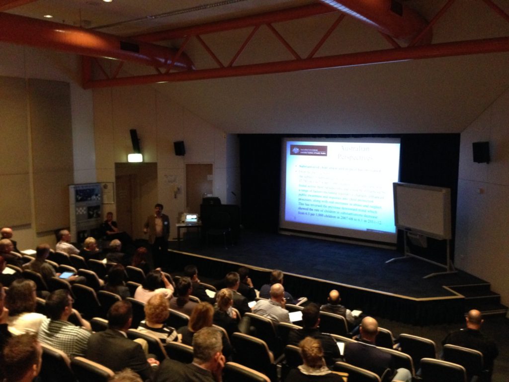 Conference audience facing a speaker and projection screen