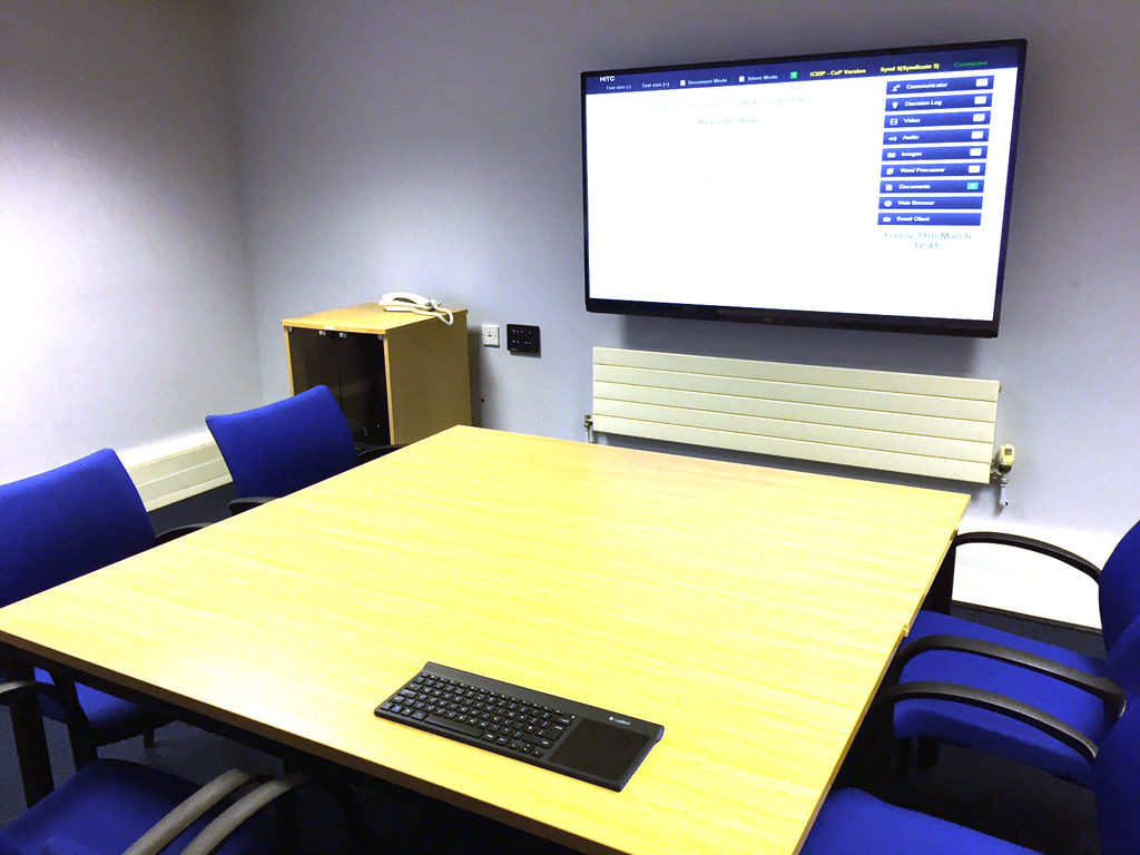 Hydra syndicate room with a meeting table and wall-mounted screen