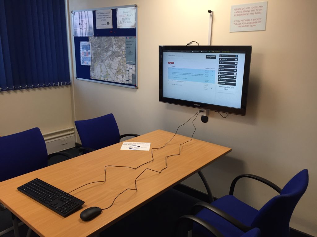 Syndicate room with a meeting table, keyboard and wall-mounted display