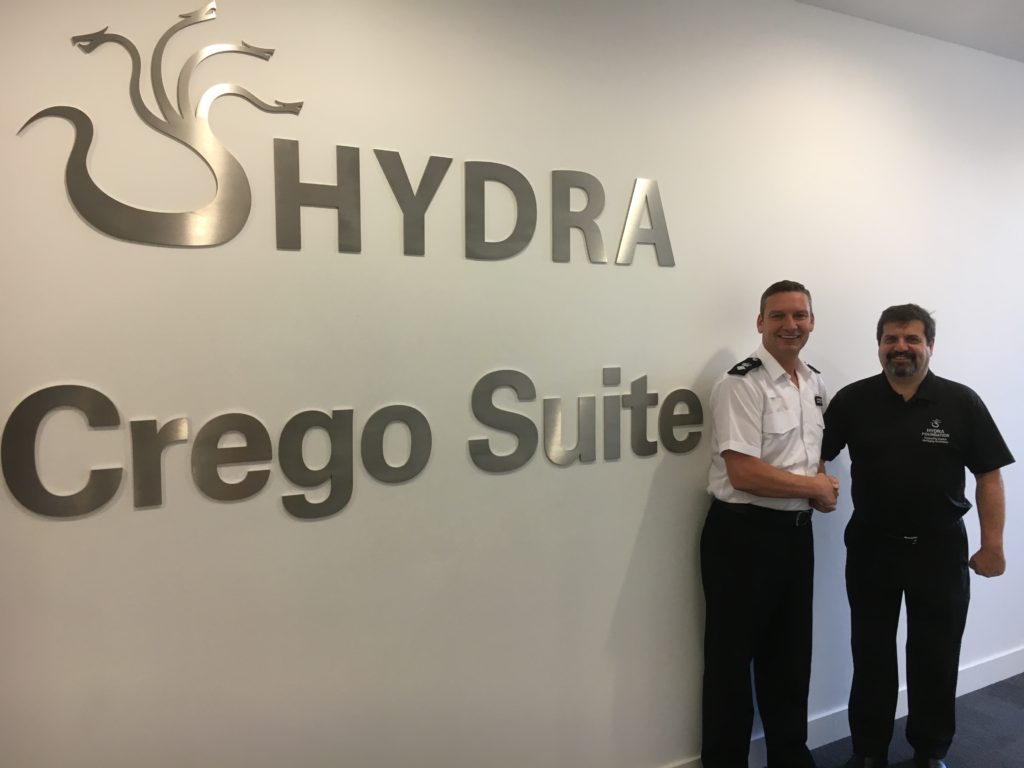 Two people standing beside a Hydra Crego Suite sign
