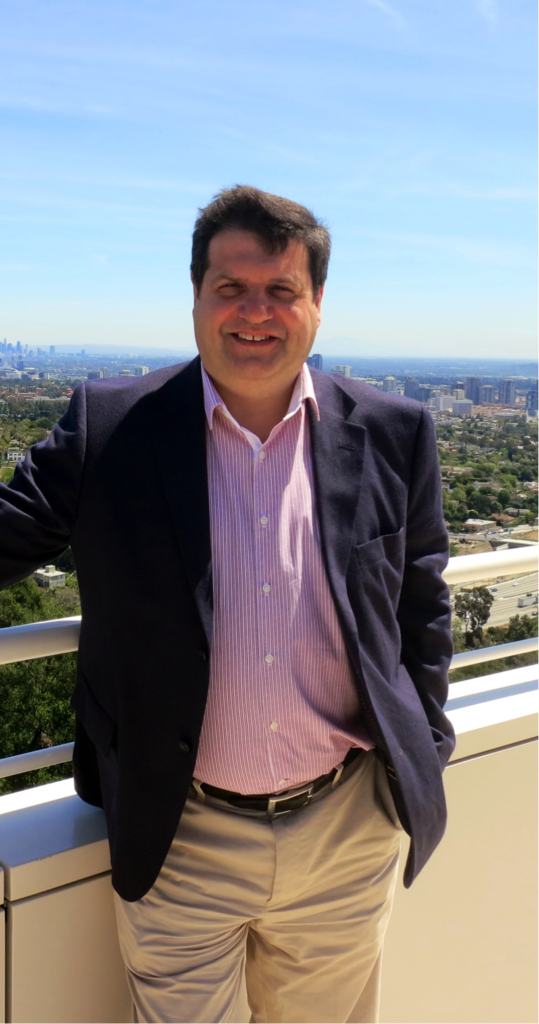 Man standing outdoors with a city skyline behind him