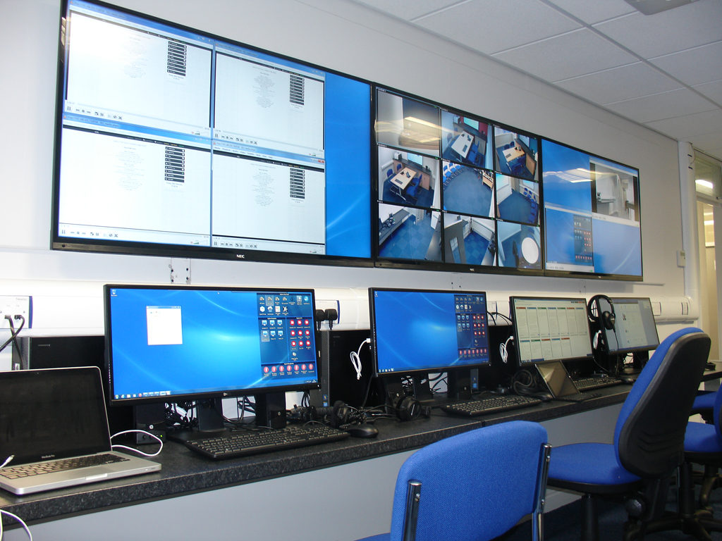 Hydra control desk with desktop computers and a bank of wall-mounted displays