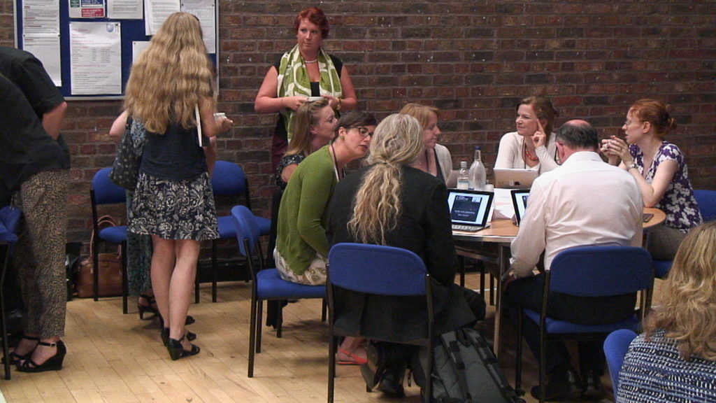 Workshop participants discussing around tables with laptops