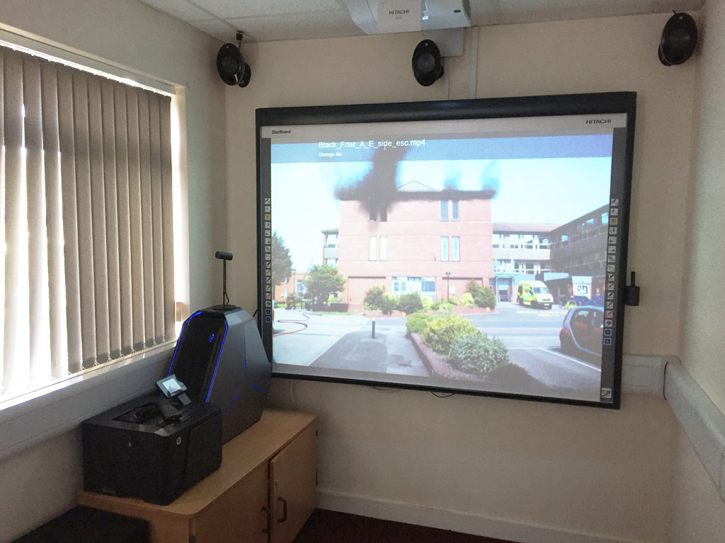 Training room with a large wall-mounted screen and speakers