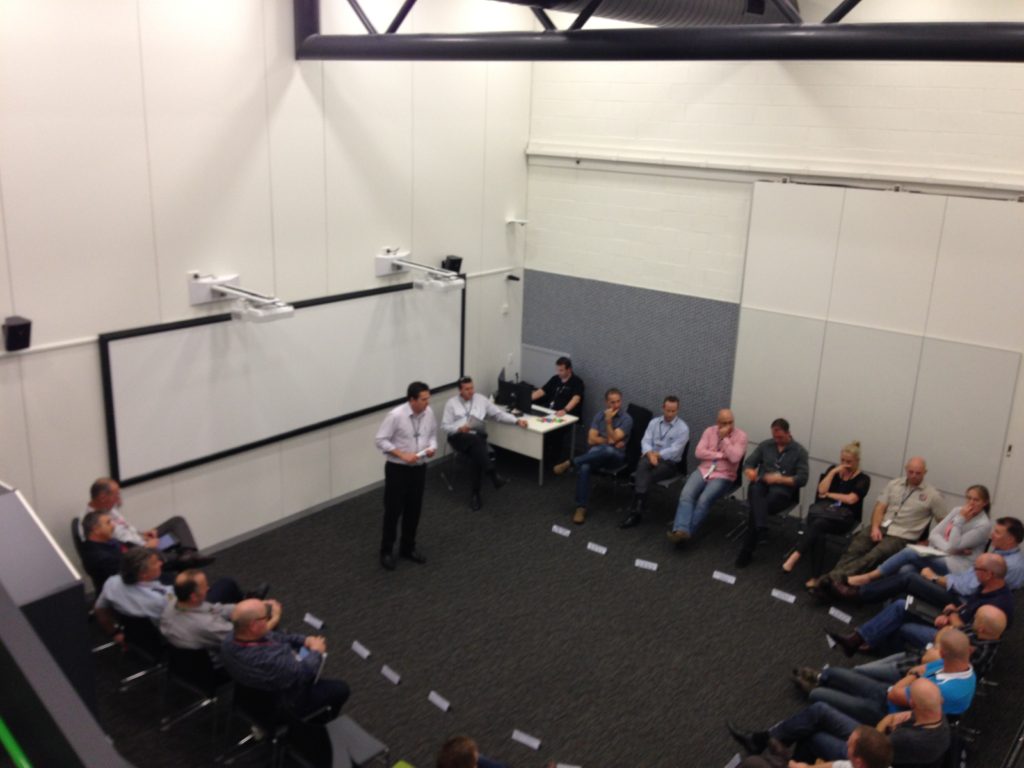 Facilitator addressing participants seated around the edge of a training room