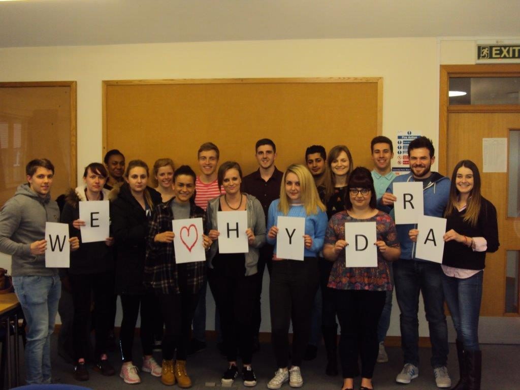 Group holding signs that spell We love Hydra